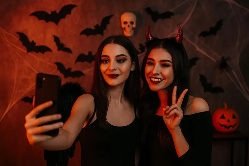 Teenager bei einer Halloween-Party vor einer Foto-Wand - eCardino